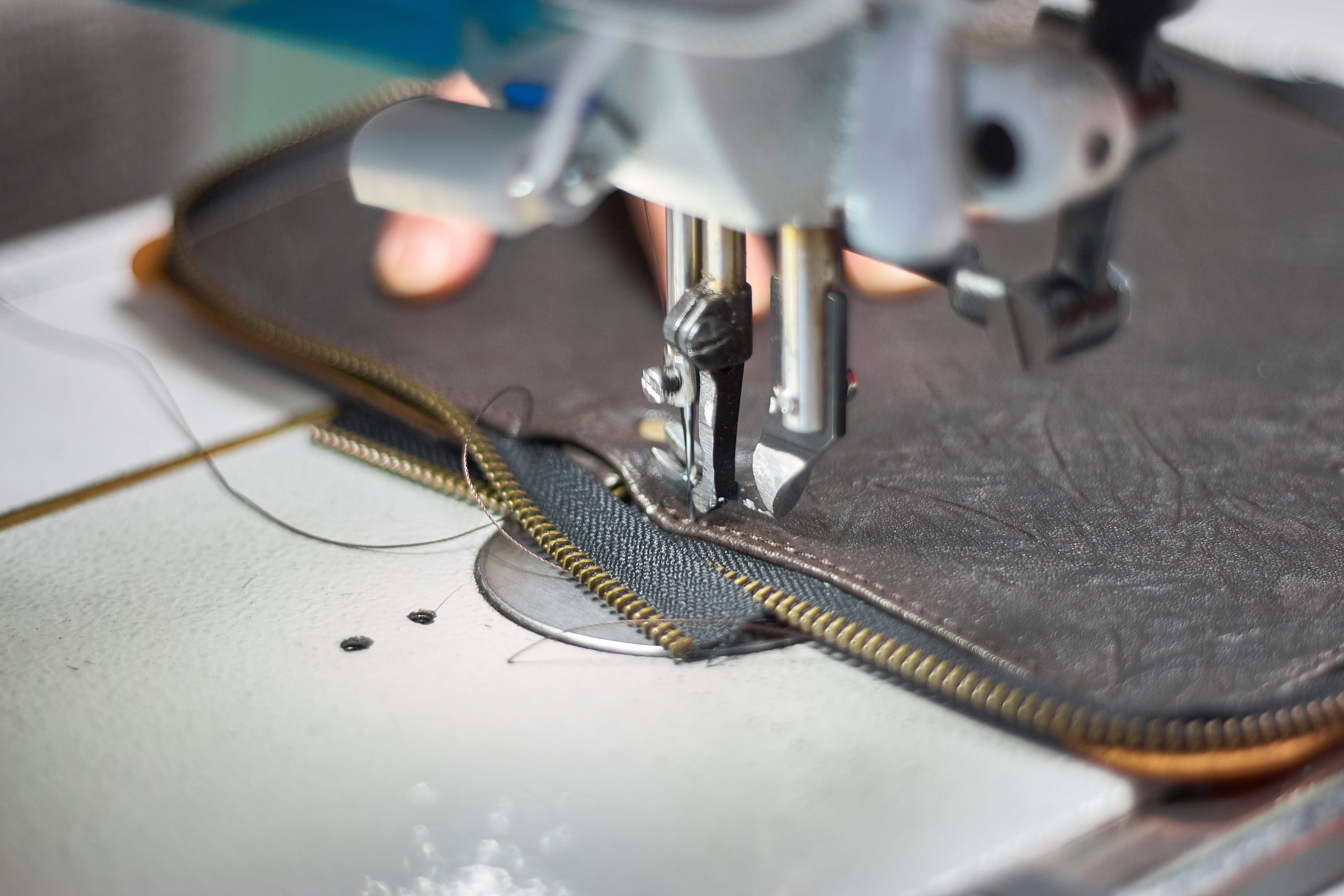 Designer stitching a fragment of a leather bag on the sewing machine close-up