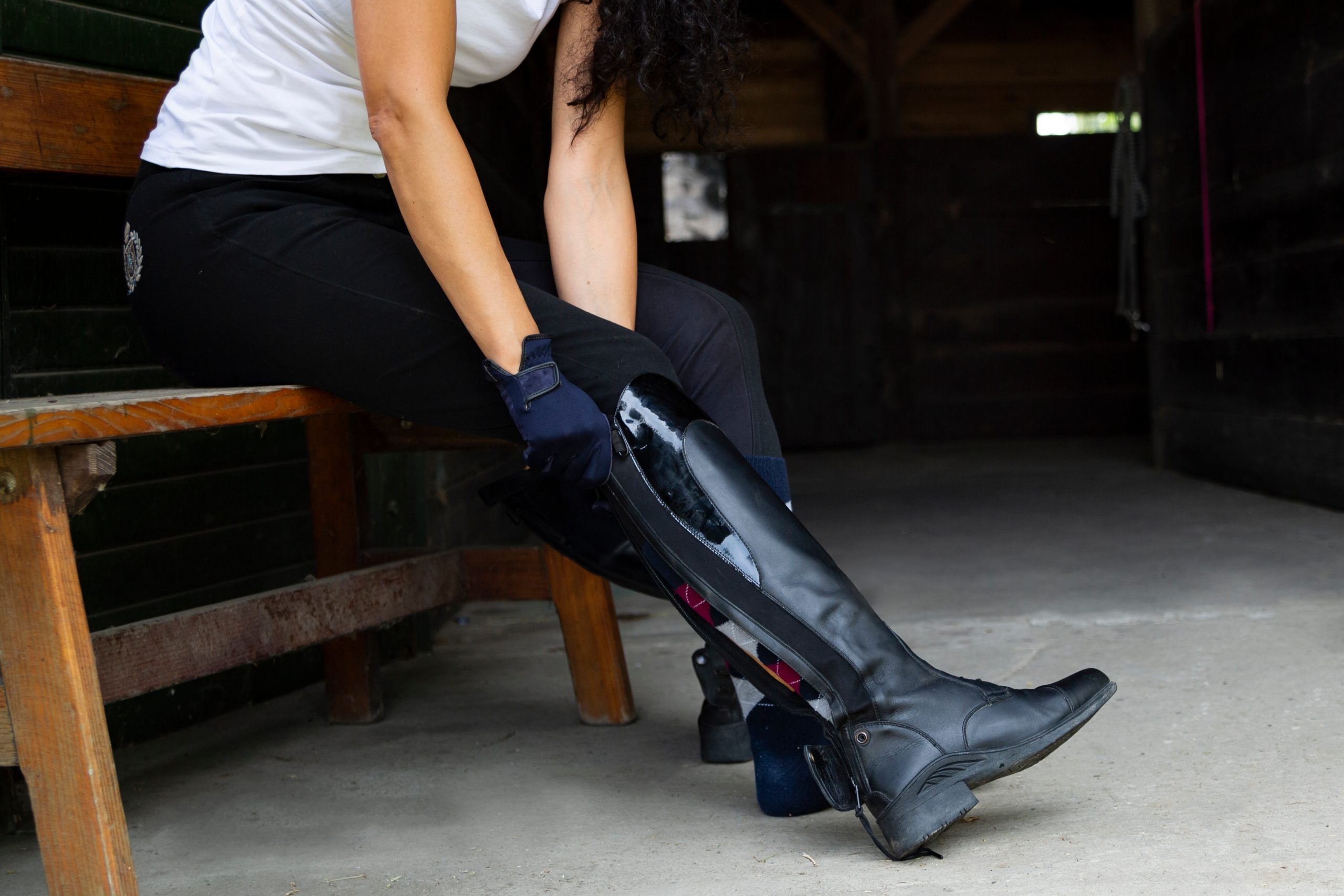 Stud, woman puts on professional leather riding boots.